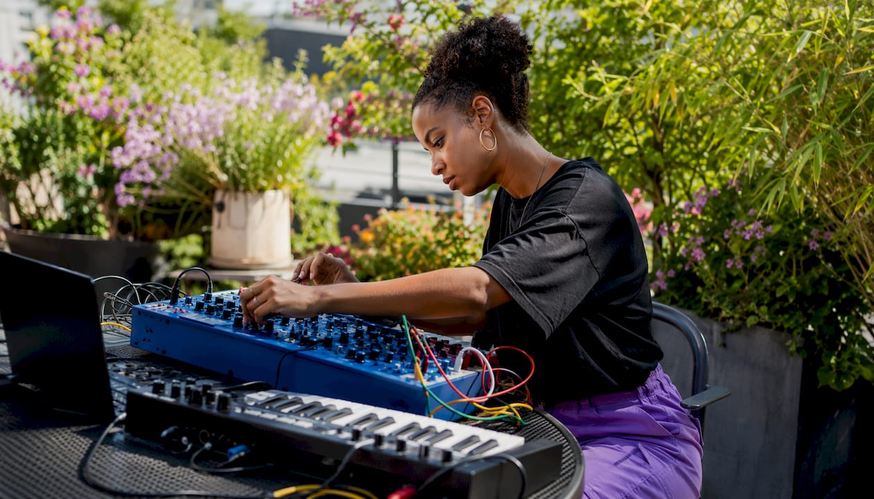 Producer adjusting analog synthesizer at desk