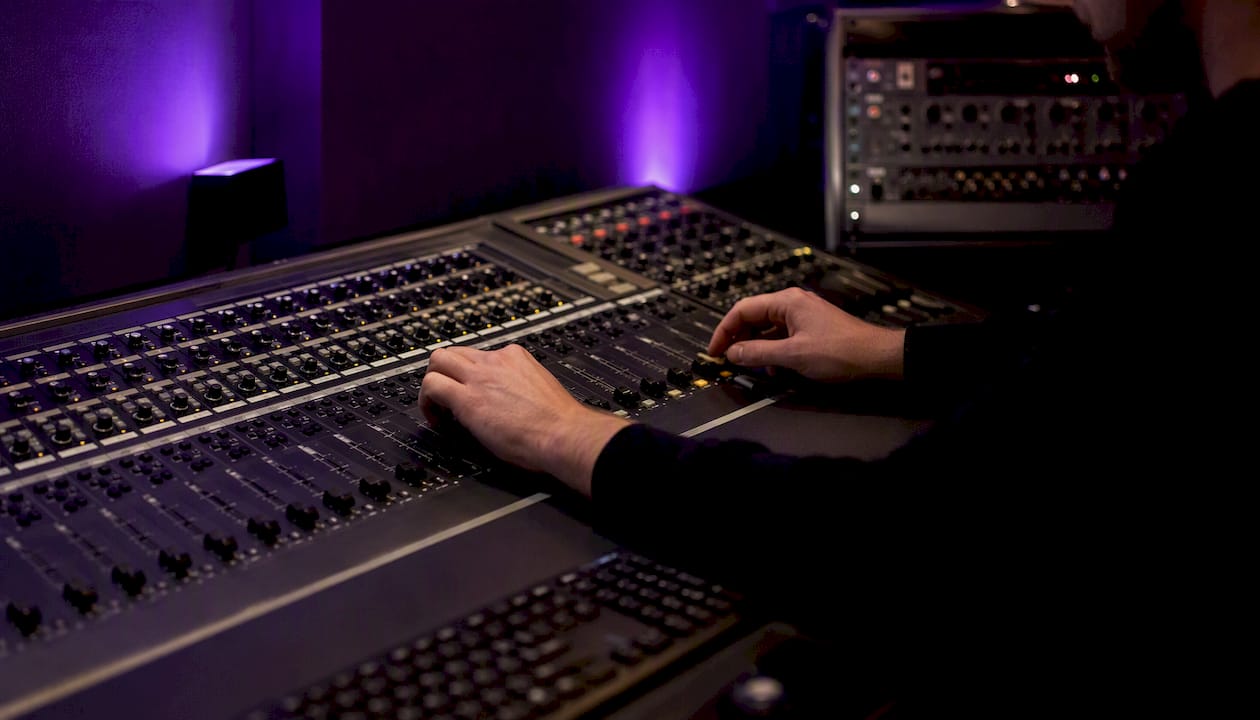Hands adjusting digital audio console knobs