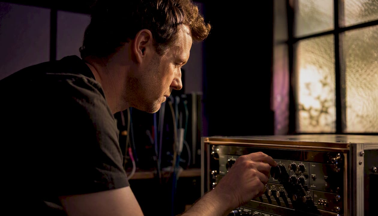 Engineer adjusting audio hardware dial in studio