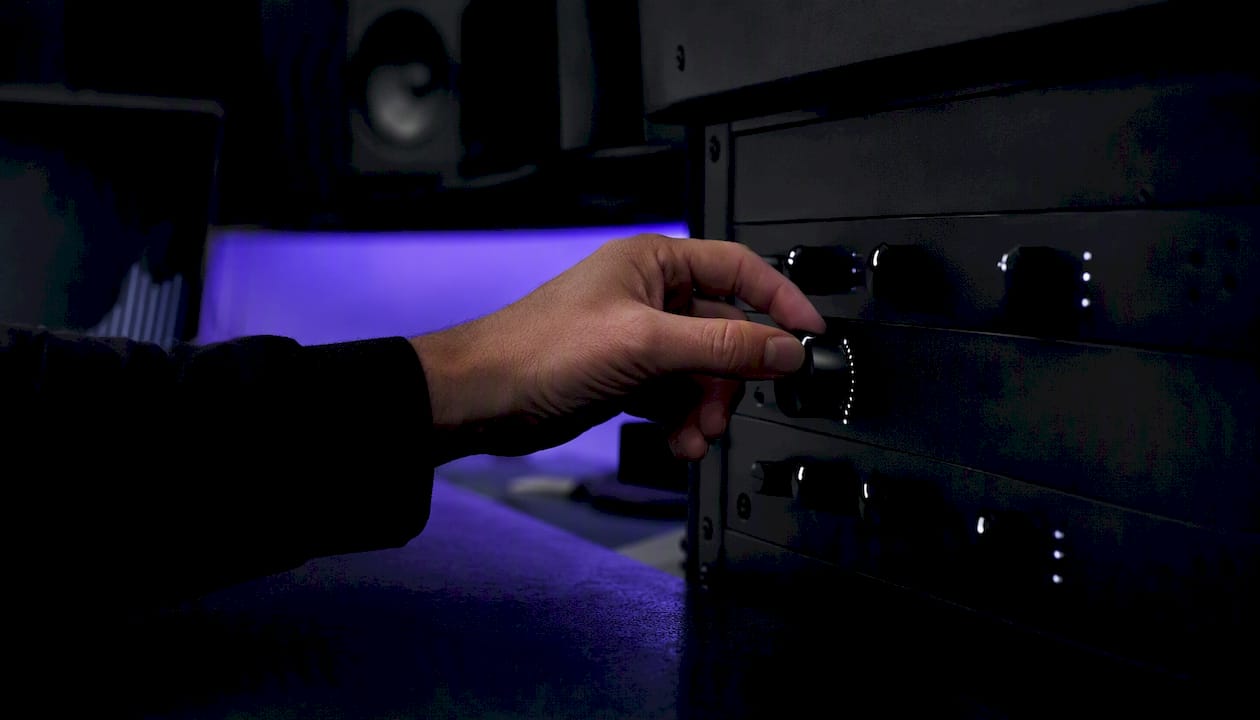 Hand adjusting limiter knob in dark studio