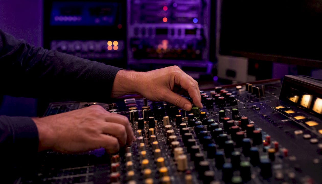 Hands connecting audio cable to mixing console