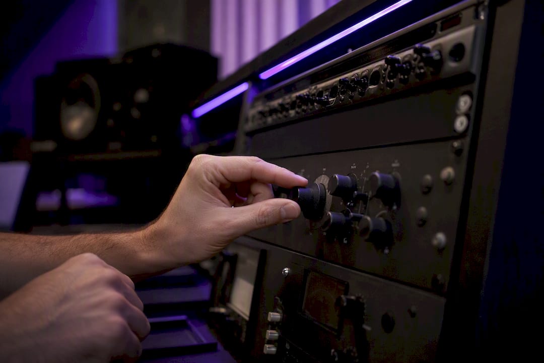 Hands adjusting analog saturation knob in studio