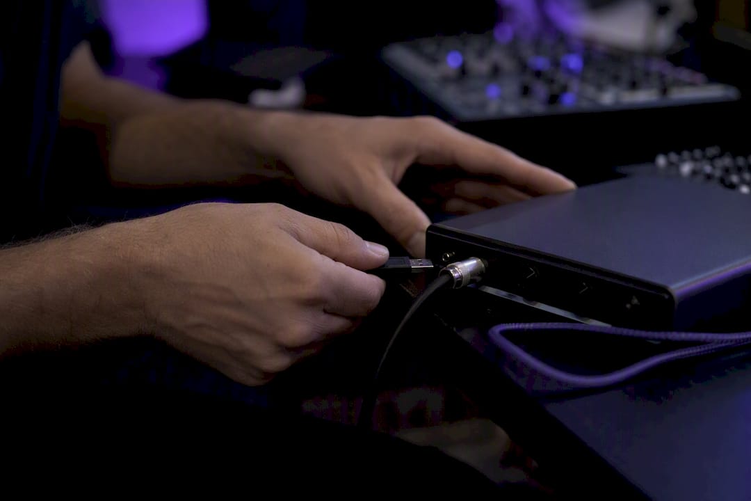 Hands connecting USB drive to audio interface
