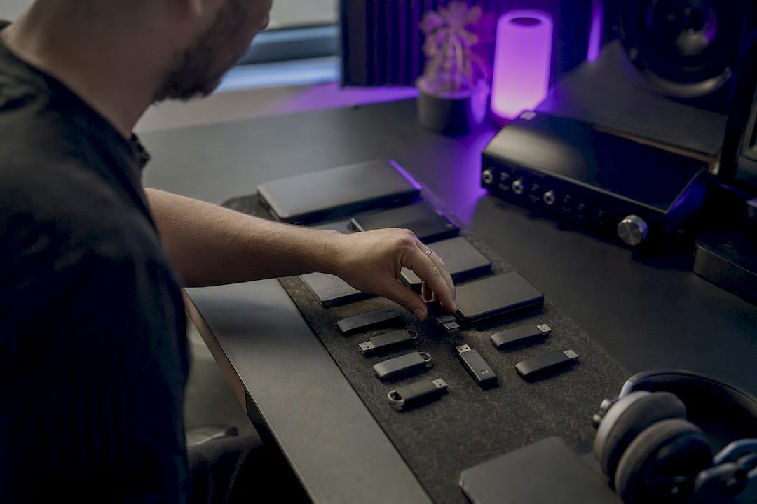 Hand plugging USB drive into hub amid organized studio desk