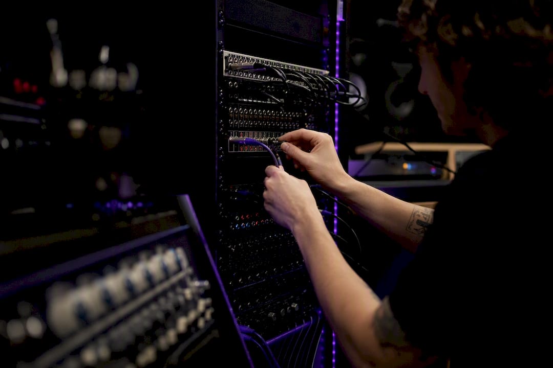 Hands connecting cables in audio rack
