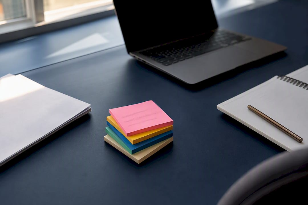 Escritorio con notas prioritarias y laptop desenfocada