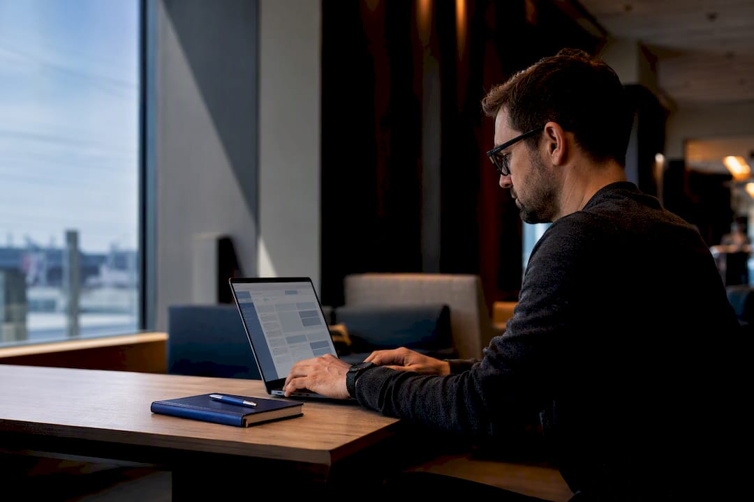 Professional prioritizing email in a station lounge
