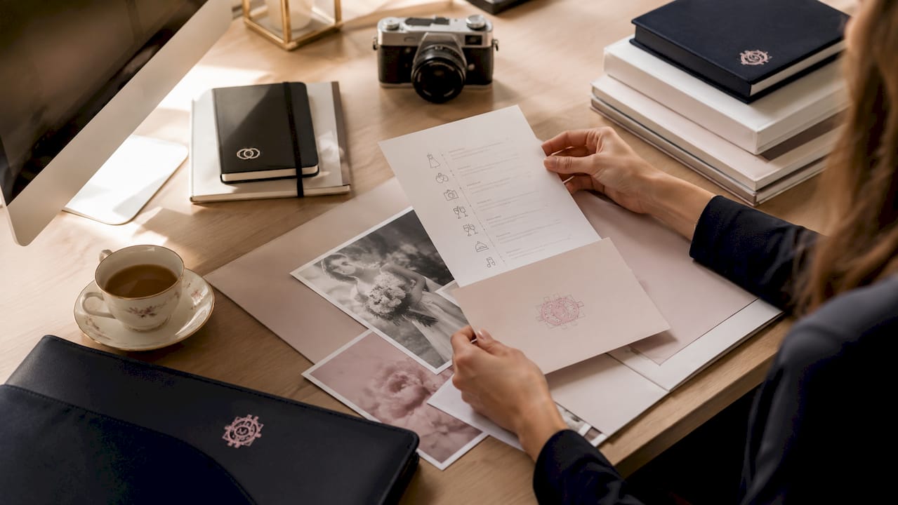 Hands arranging wedding contracts and albums on desk