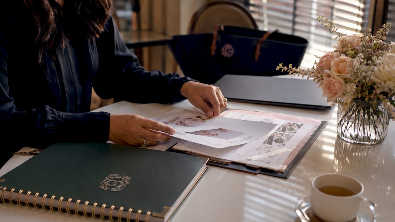 Hands arranging wedding vendor documents on desk