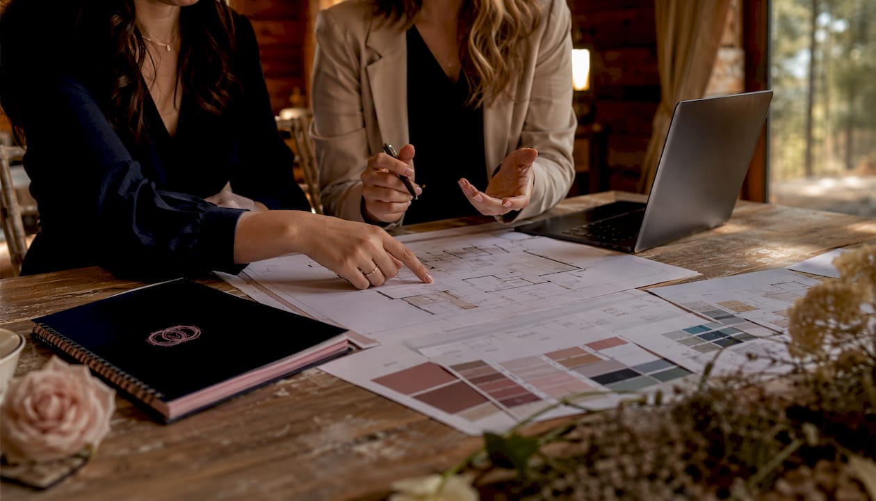 Hands pointing at wedding floor plans on desk