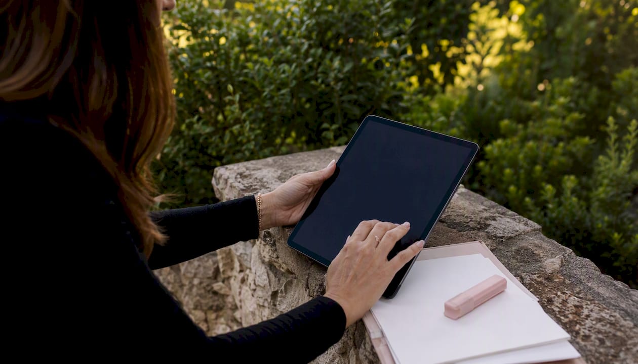 Planner’s hands on tablet with wedding materials