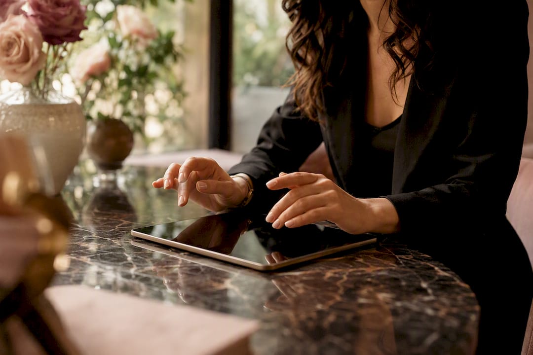Hands over tablet with wedding rings nearby