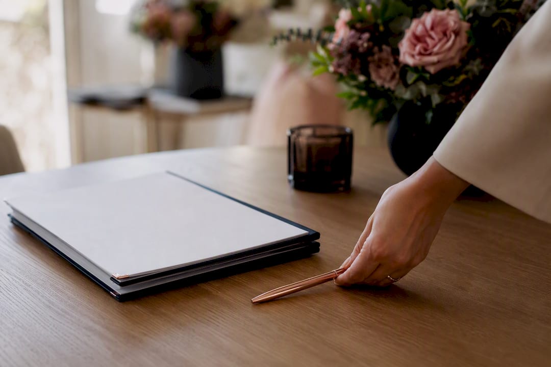 Hand placing pen near unopened contract folder