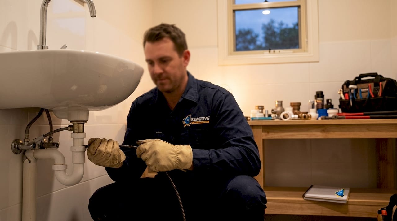 Plumber using drain snake on sewer pipe