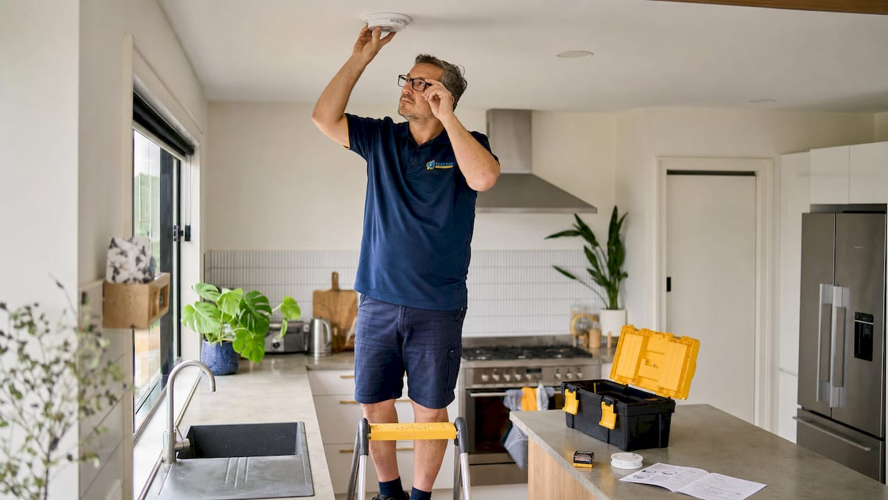 Homeowner replacing smoke alarm on ceiling