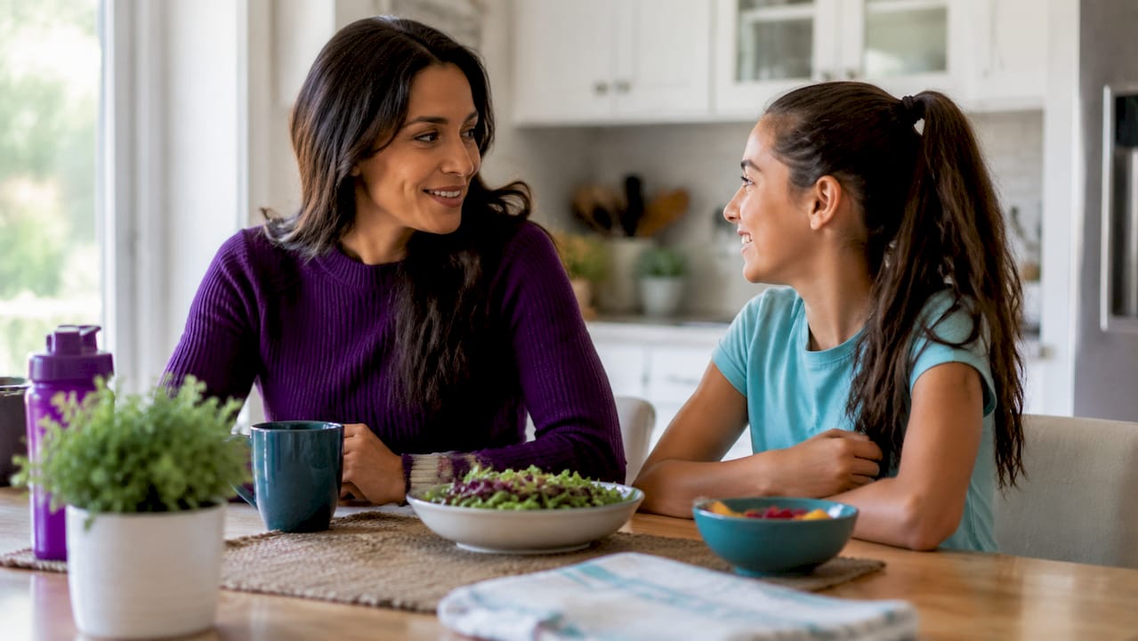 Mother comforting teenage daughter on couch