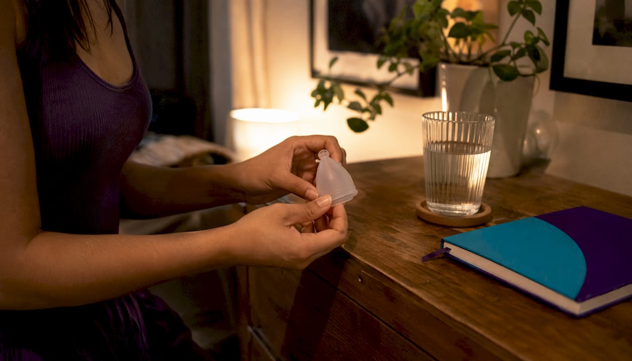 Hands checking menstrual cup placement in bathroom