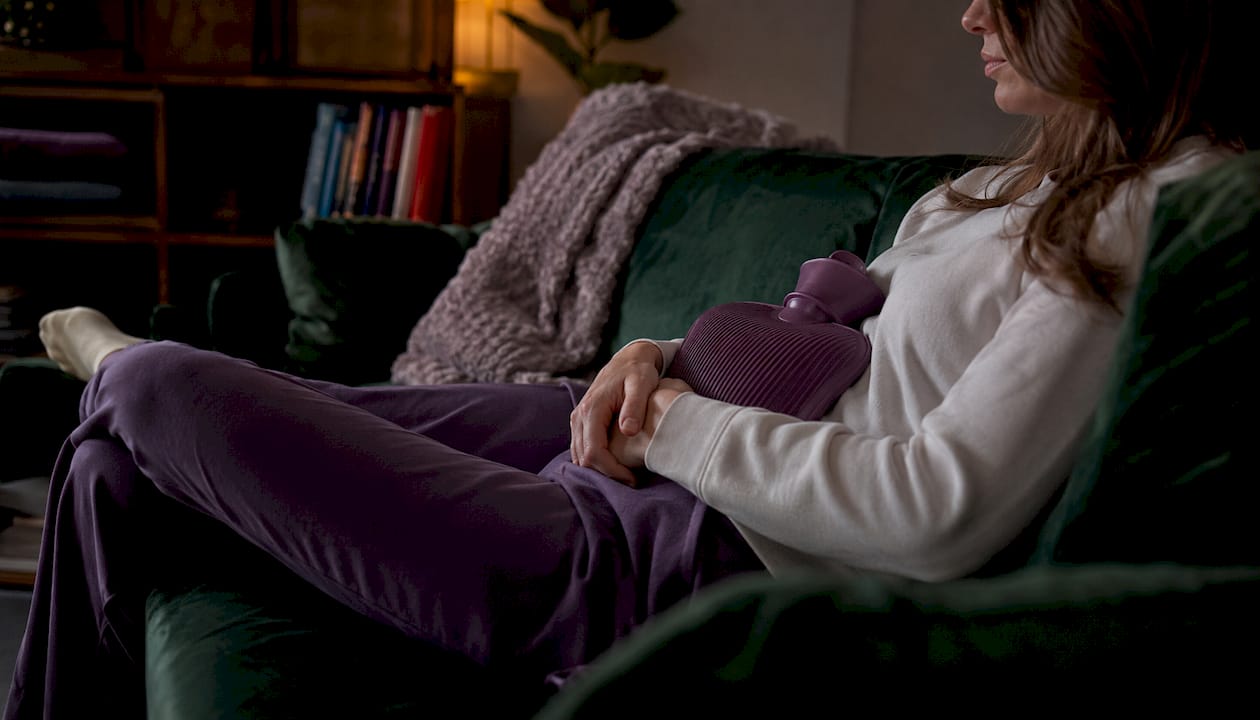 Hands holding hot water bottle for cramps relief