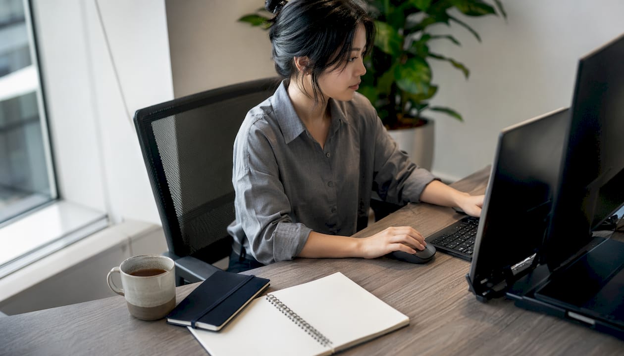 Des mains en train de saisir sur un clavier, posées sur un bureau épuré.
