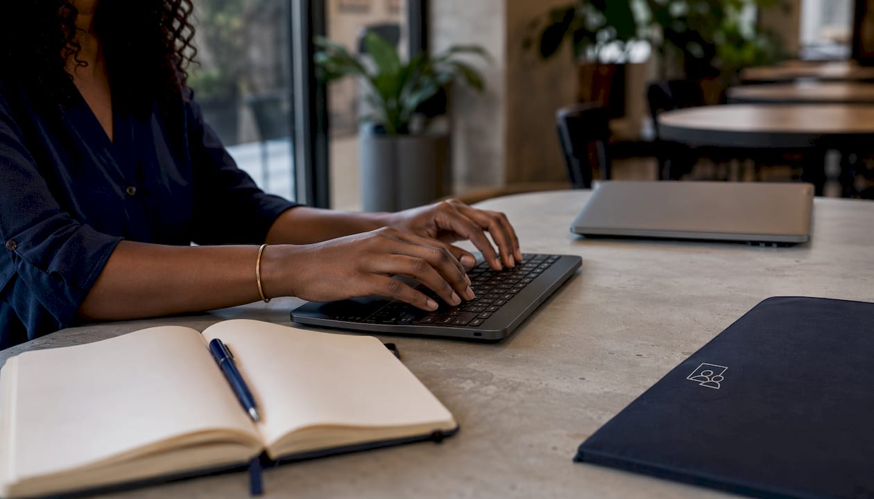 Une femme travaille sur son ordinateur portable dans un bureau contemporain, ses mains courant sur le clavier.