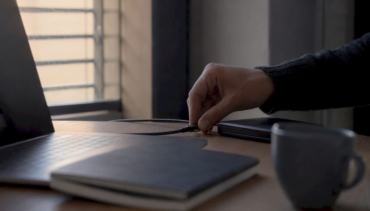 Une main branche un câble sur un disque dur externe.