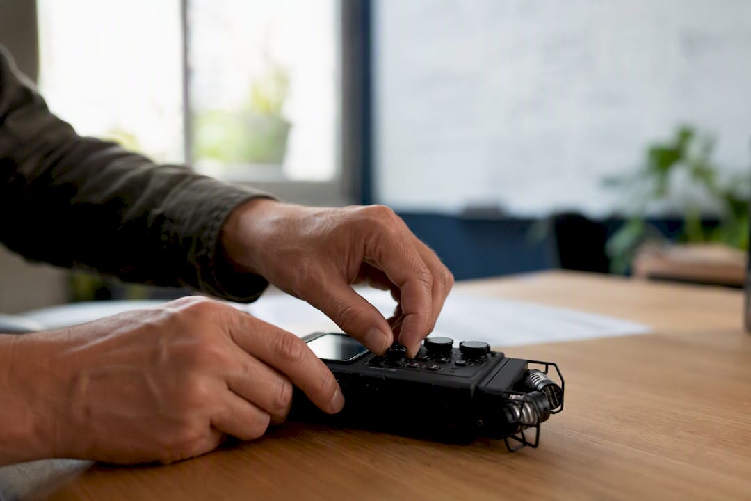 Des mains en train de régler un enregistreur audio