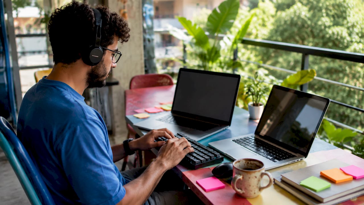 Hands typing on keyboard with dual laptops