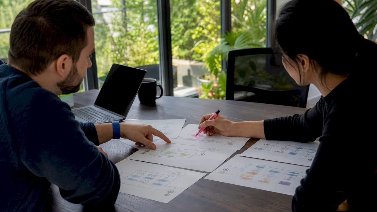Hands discussing AI agent architecture diagrams at table
