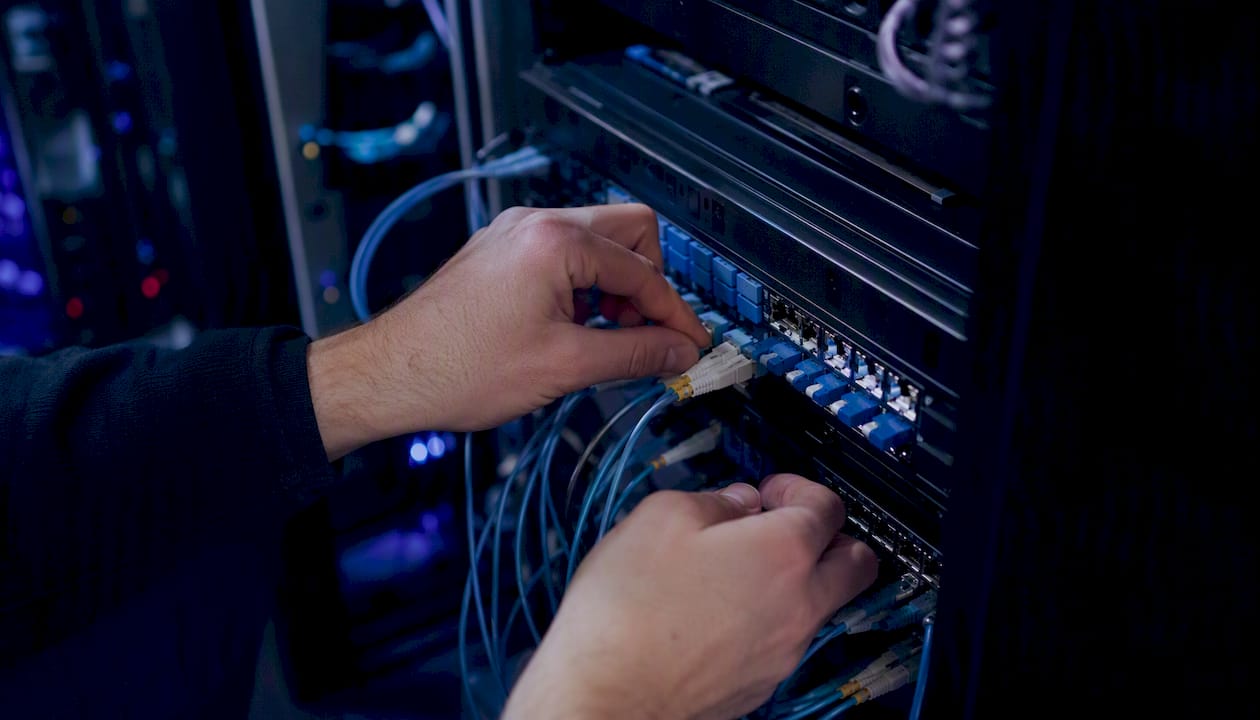Hands wiring AI data routing panel