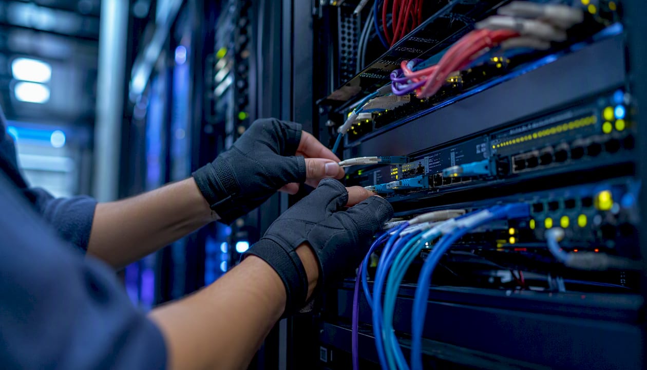 Hands switching fiber optic cable on network panel
