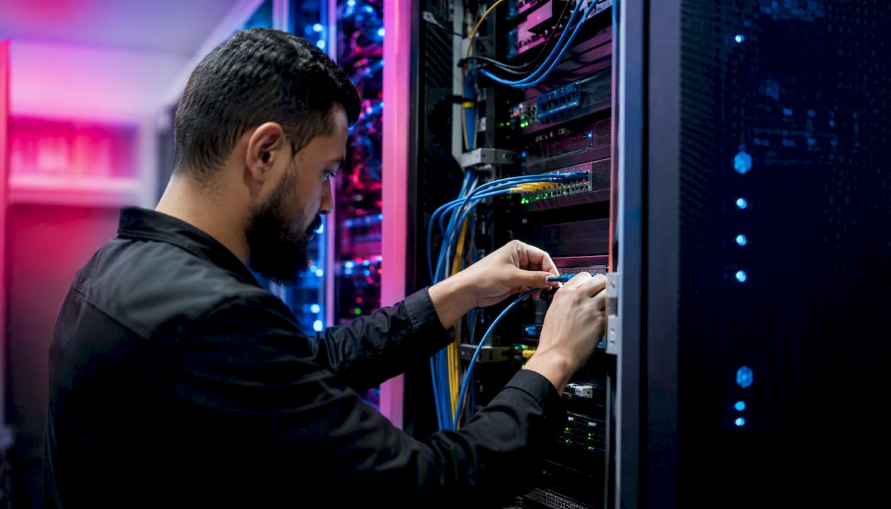 Technician connecting cables in server rack