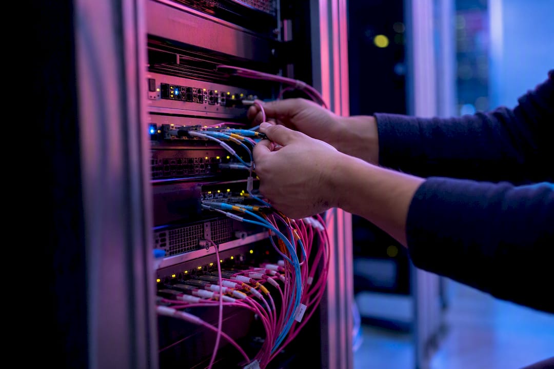 Hands connecting fiber optic cable in server room