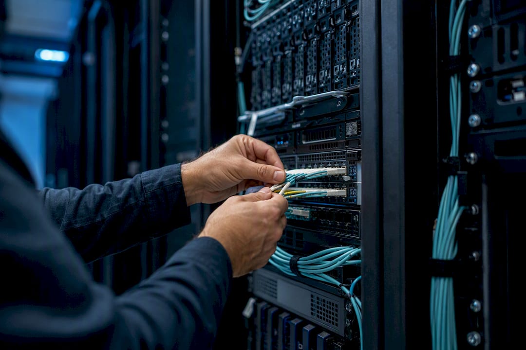 Hands managing multiple fiber optic cables in data center