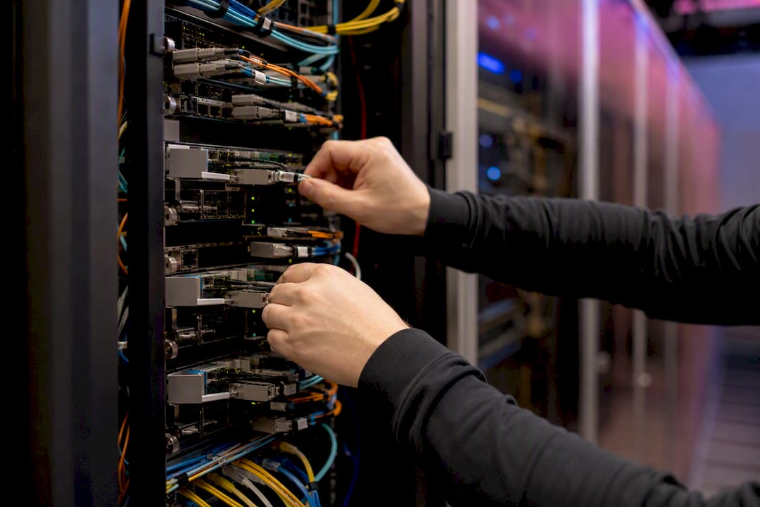 Hands managing network cables in data center