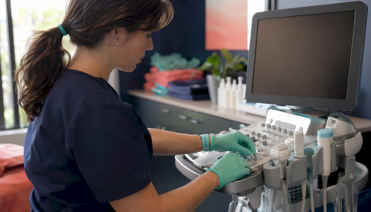 Hands adjusting ultrasound machine controls in radiology