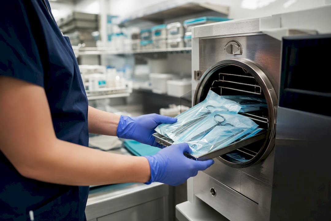 Hands loading tools into autoclave sterilizer