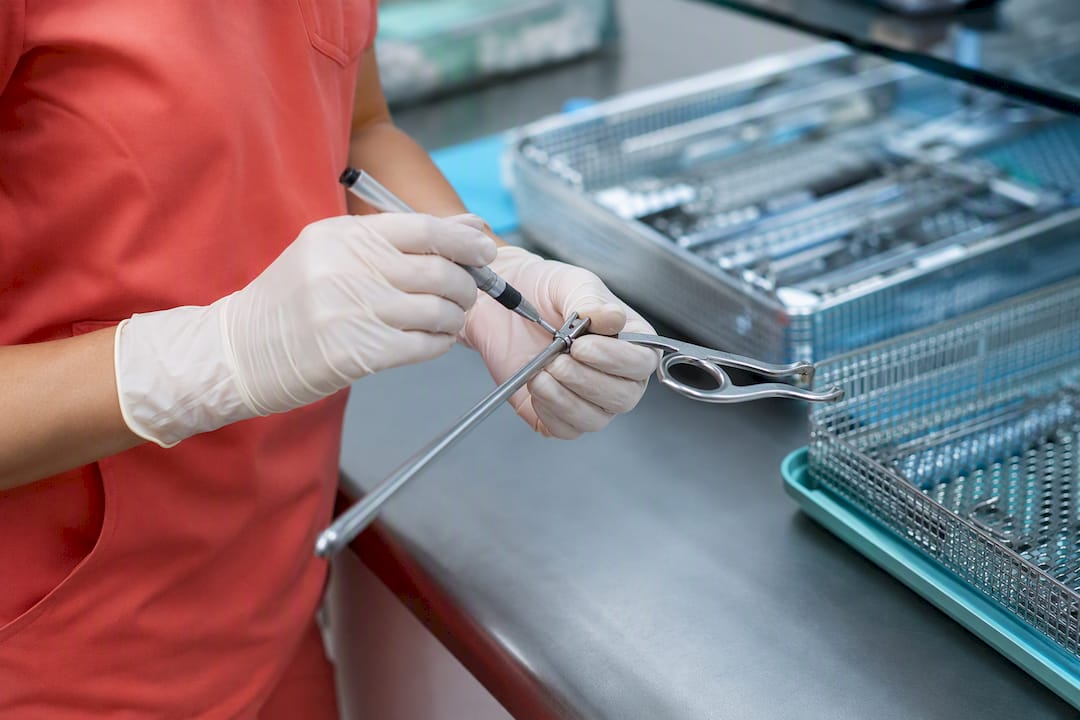 Technician applying lubricant to surgical instrument
