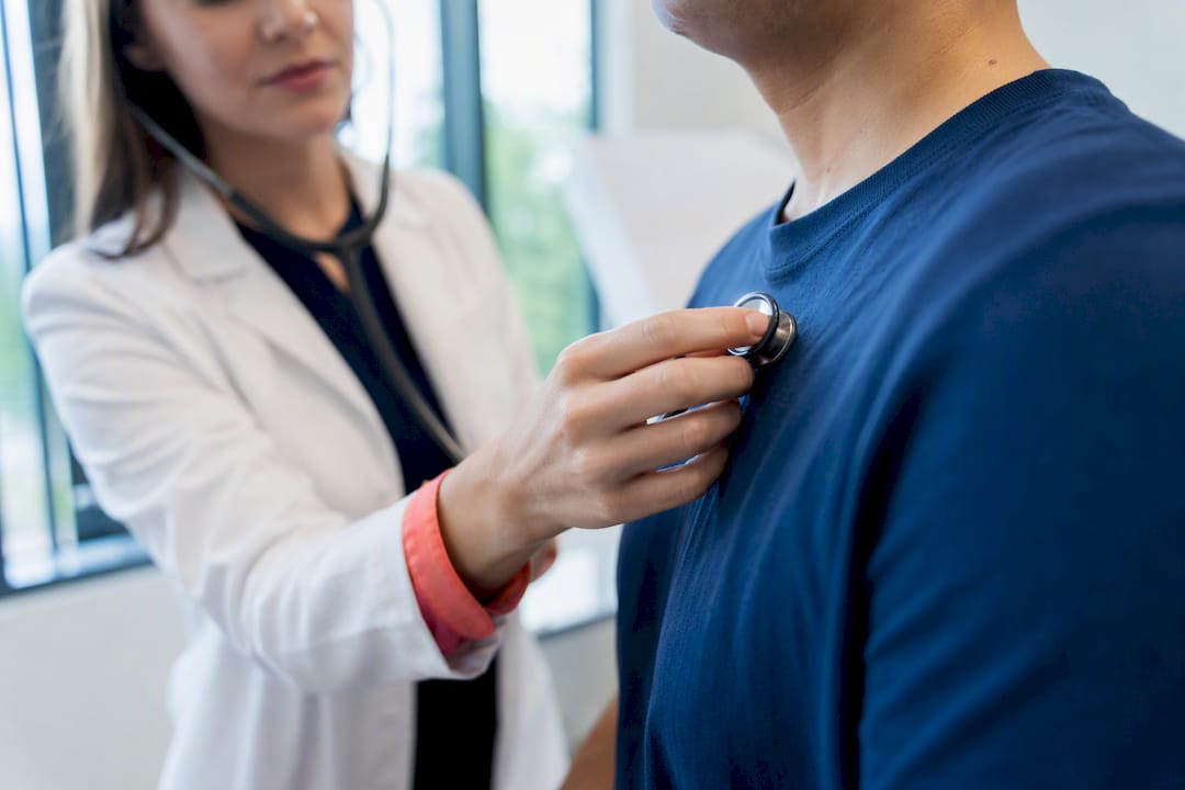 Clinician using stethoscope during clinic examination