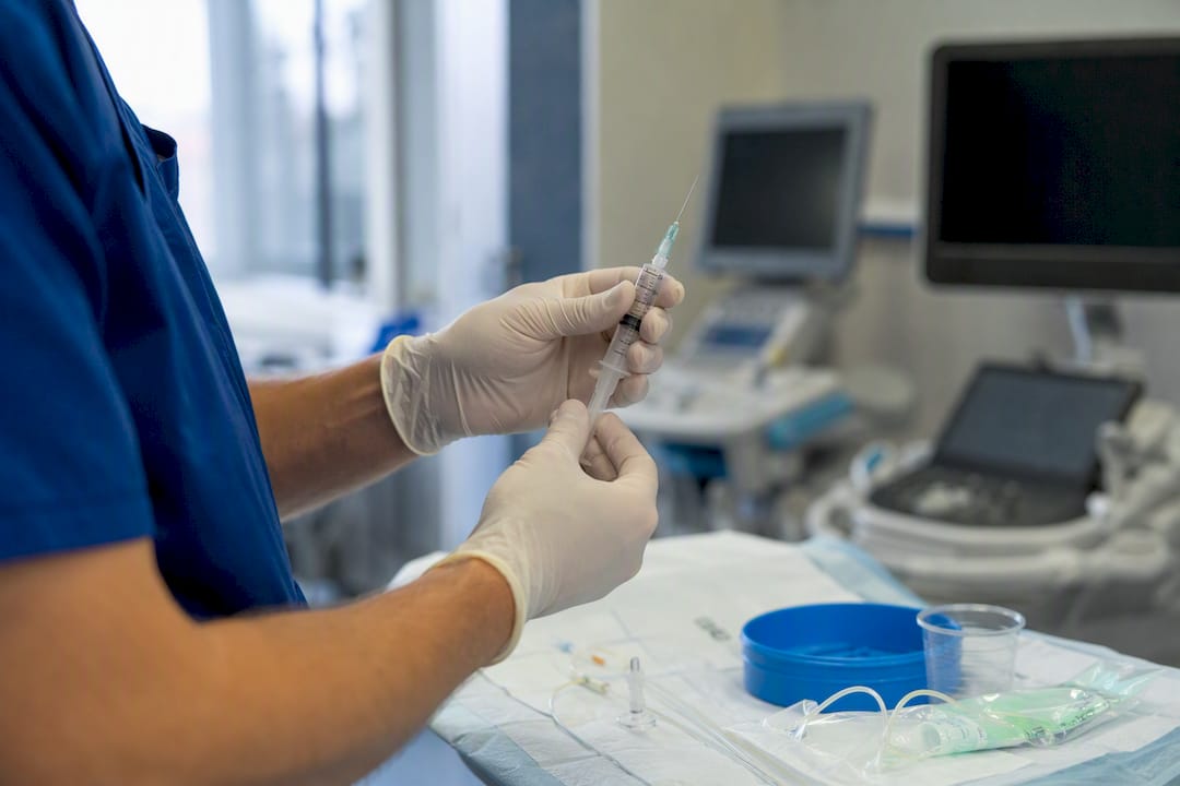 Mâini pregătind o seringă pentru injecție spinală