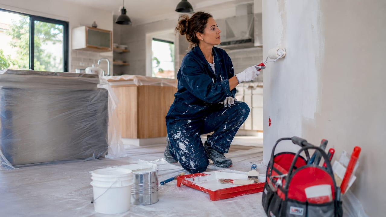 Profesional pintando una pared interior con imprimación en una vivienda