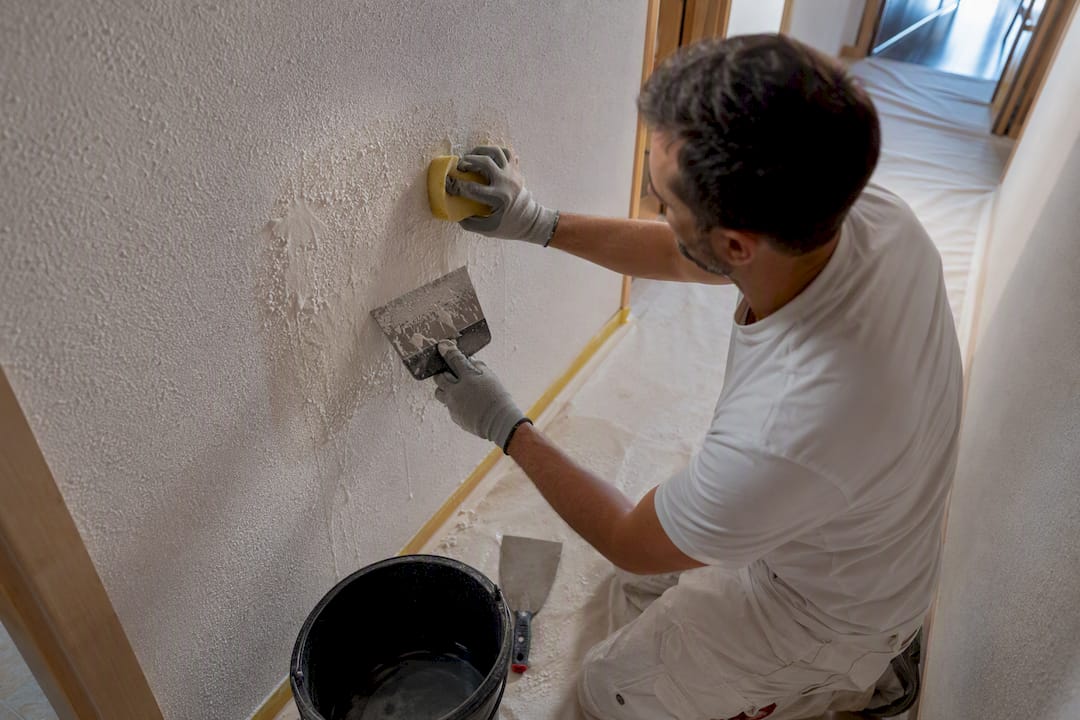 Profesional humedeciendo y raspando el gotelé
