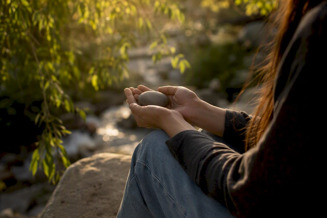 Hands holding grounding stone outdoors
