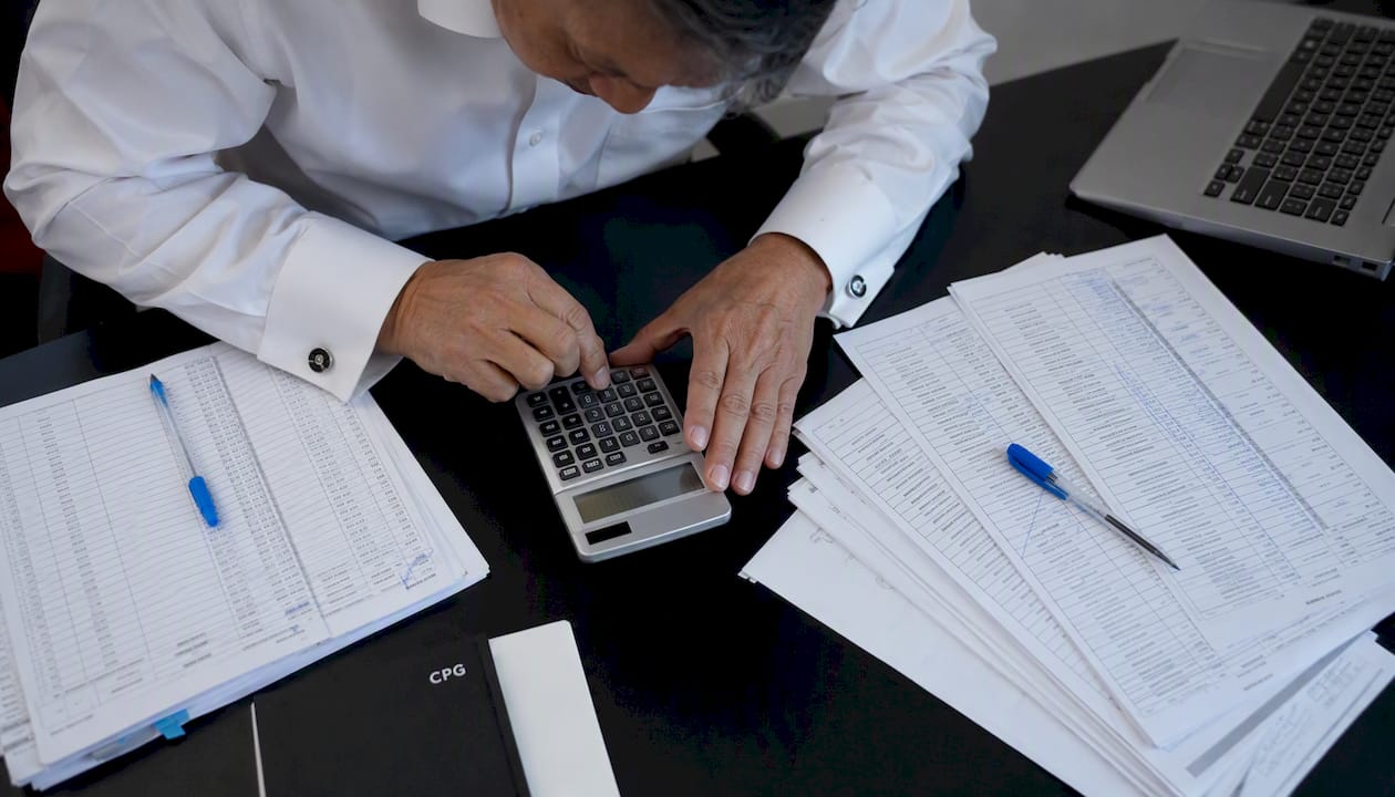 Hands using calculator on trade spend data