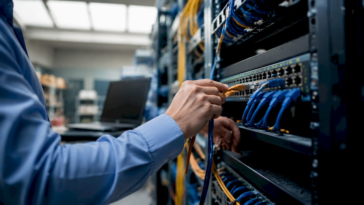 Hands connecting patch cord to network switch