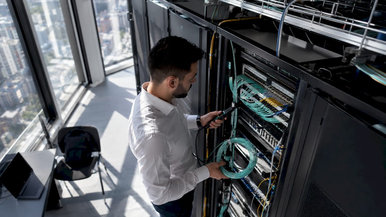 Engineer inspecting fiber optic patch panel in server room