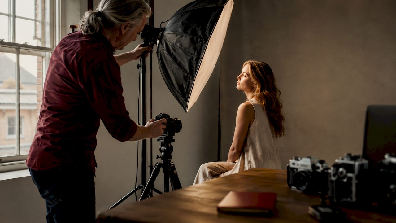 Photographer adjusting softbox light in beauty shoot studio