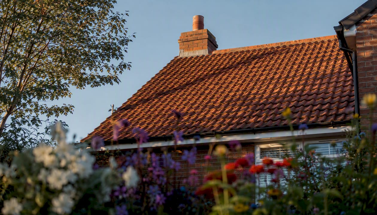 Shadows on UK home's terracotta roof from chimney and trees