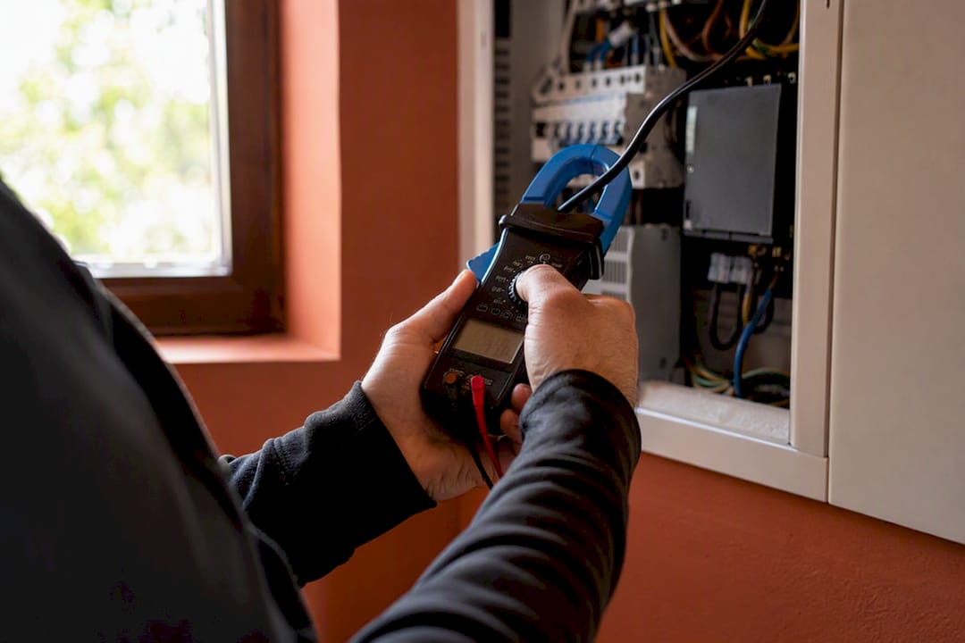 Hands measuring home electrical current