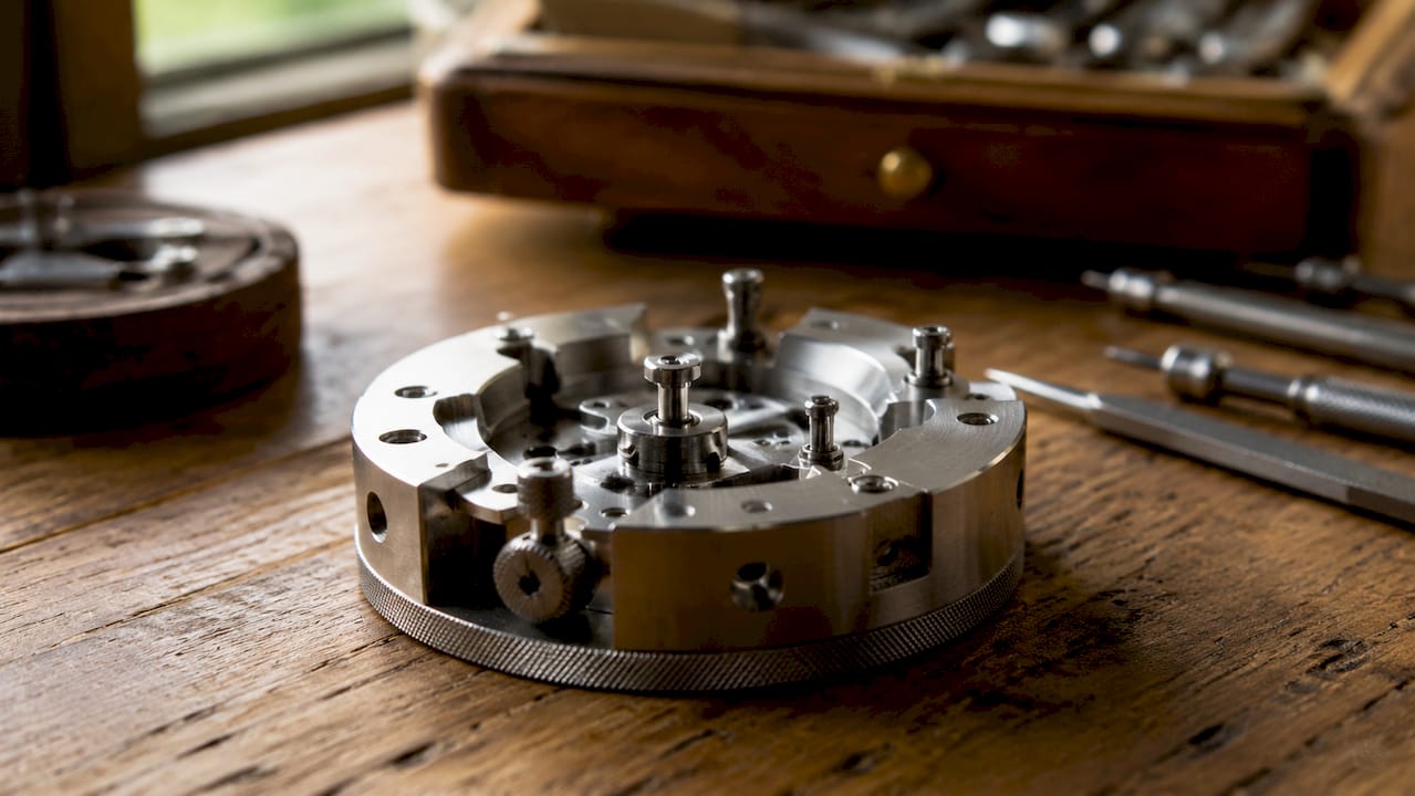 Close-up of metal watch movement holder on white surface