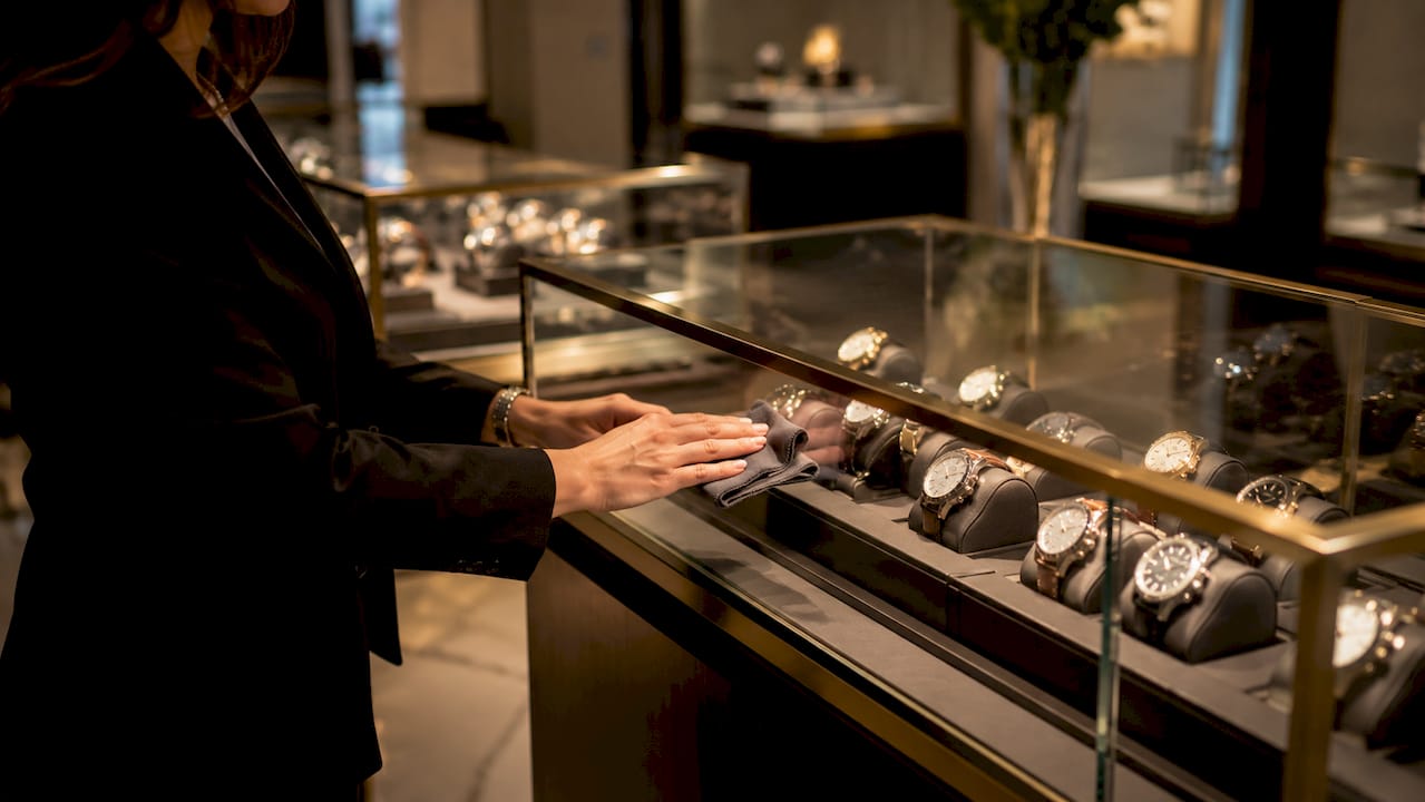 Hands cleaning glass watch display with cloth